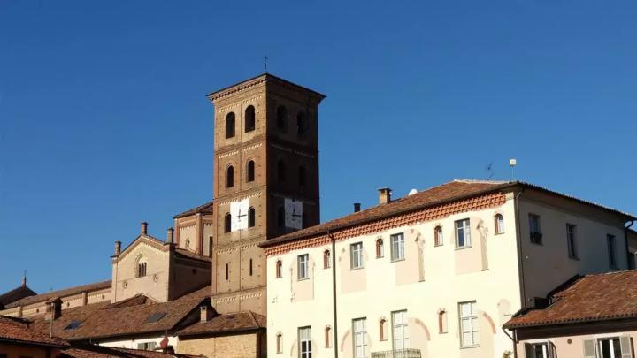 Fianco di chiesa e campanile medievale in mattoni e facciata di palazzo con resti di finestre medievali 