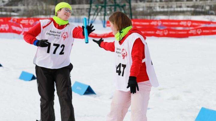 Due giovani in abiti sportivi invernali sulla neve si passano la staffetta