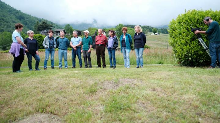 Gruppo di persone in fila in campagna riprese da cinepresa