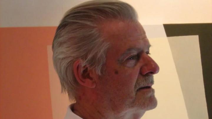 Immagine fotografica dell'artista con un dipinto astratto sullo sfondo