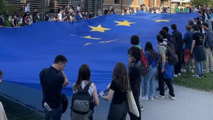 Giovani all'aperto sorreggono grande bandiera europea