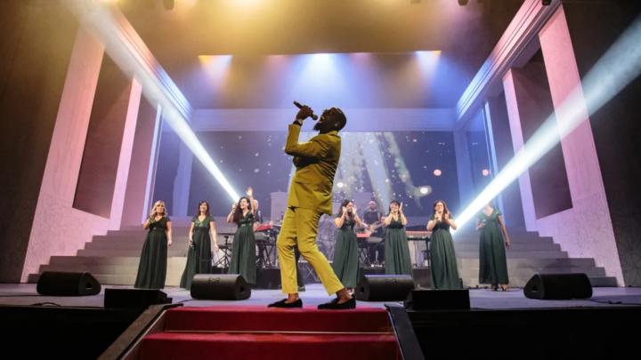 Foto: solista maschile e coro gospel in concerto con fasci di luce su palcoscenico