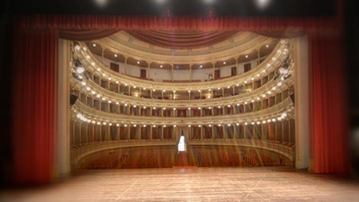 Sala di teatro all'italiana a ferro di cavallo con palchi sovrapposti, vista dal palco con sipario aperto