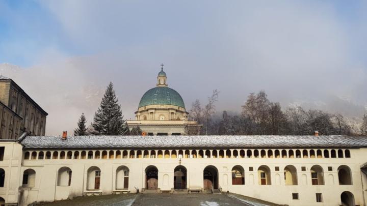 Chiostro e sullo sfondo la cupola del Santuario superiore di Oropa, con neve