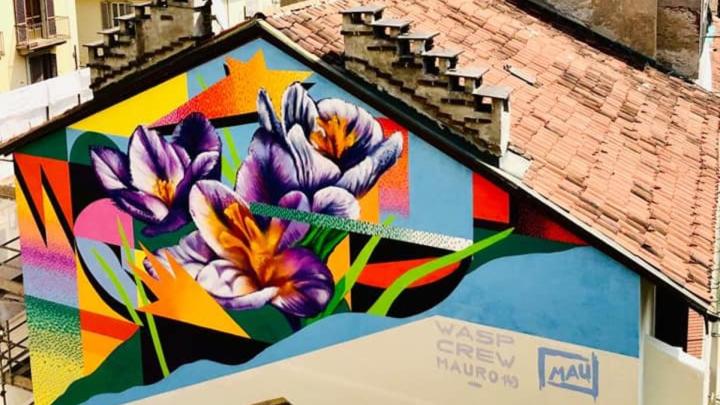 Musales firmato con fiori e motivi astratti sul muro esterno di una casa 